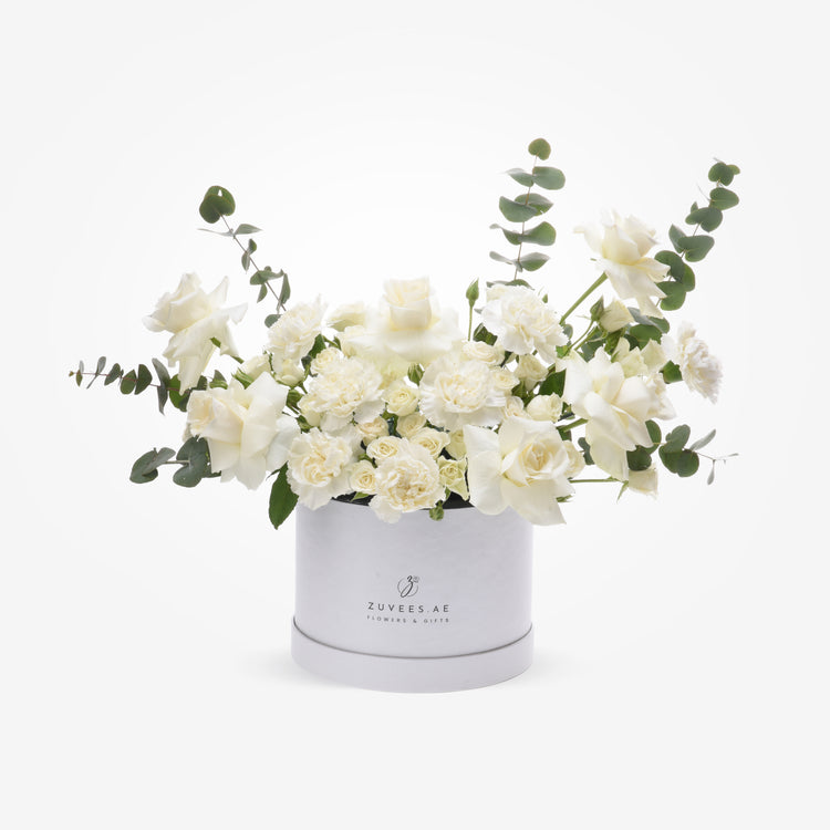 Elegant white rose and eucalyptus arrangement in branded silver hat box.
